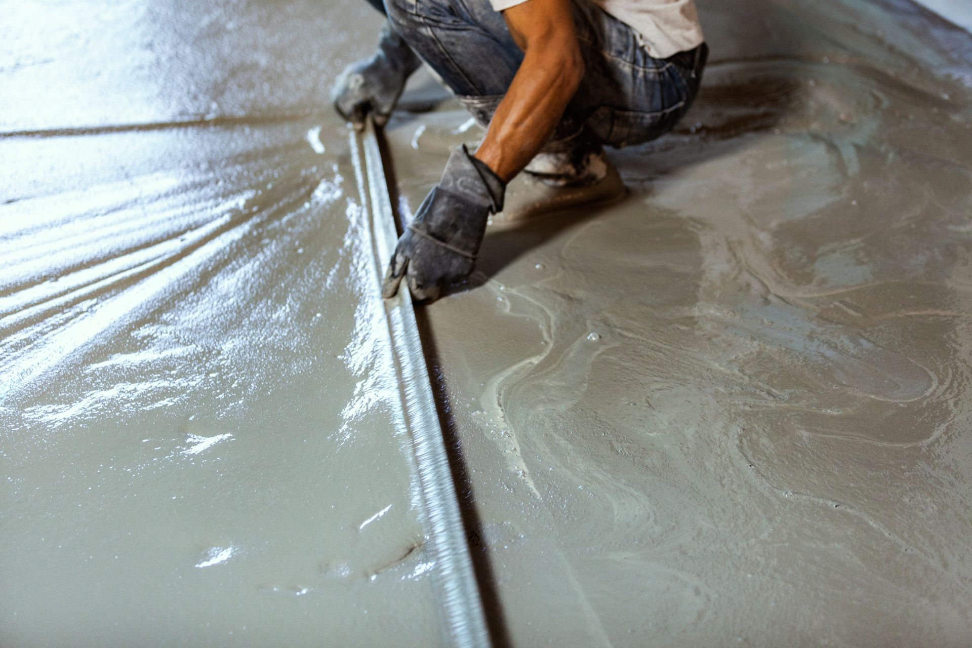 Close-up image of a construction contractor smoothing the wet concrete floor. Close-up image of a construction contractor smoothing the wet concrete floor.