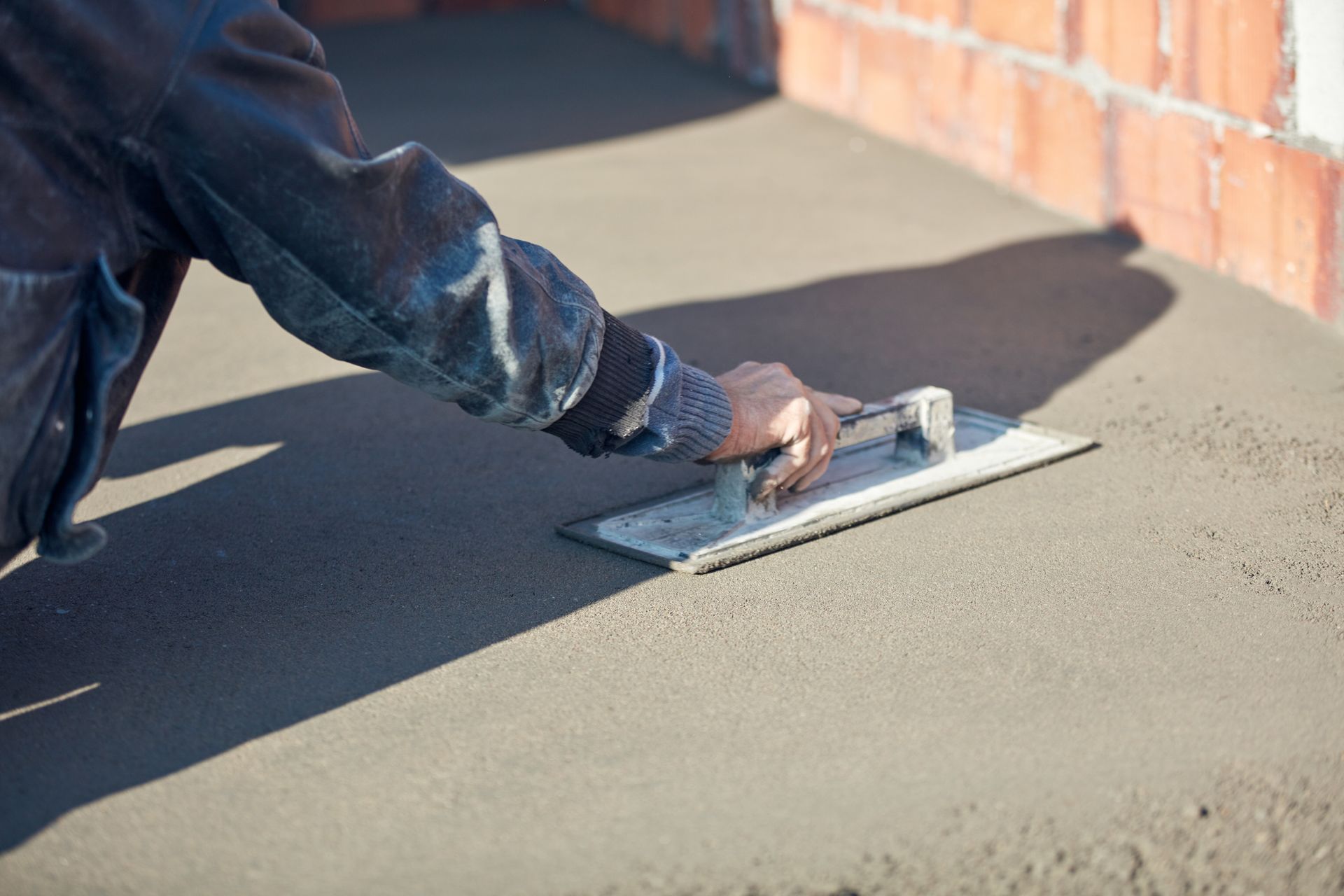 Close-up of a construction worker leveling concrete pavement. Close-up of a construction worker leveling concrete pavement.