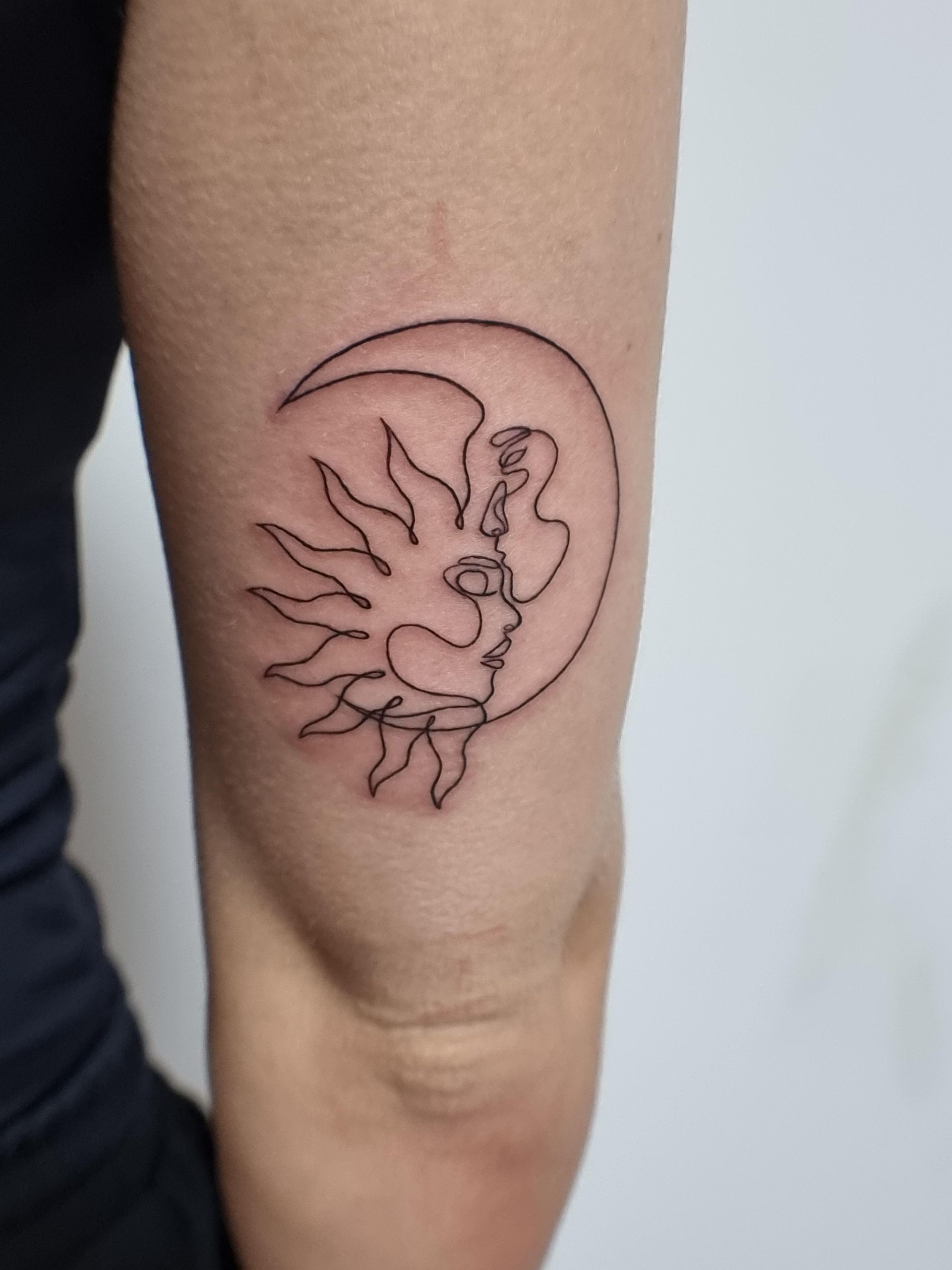 Eine Frau hat eine Tätowierung von Sonne und Mond auf ihrem Arm