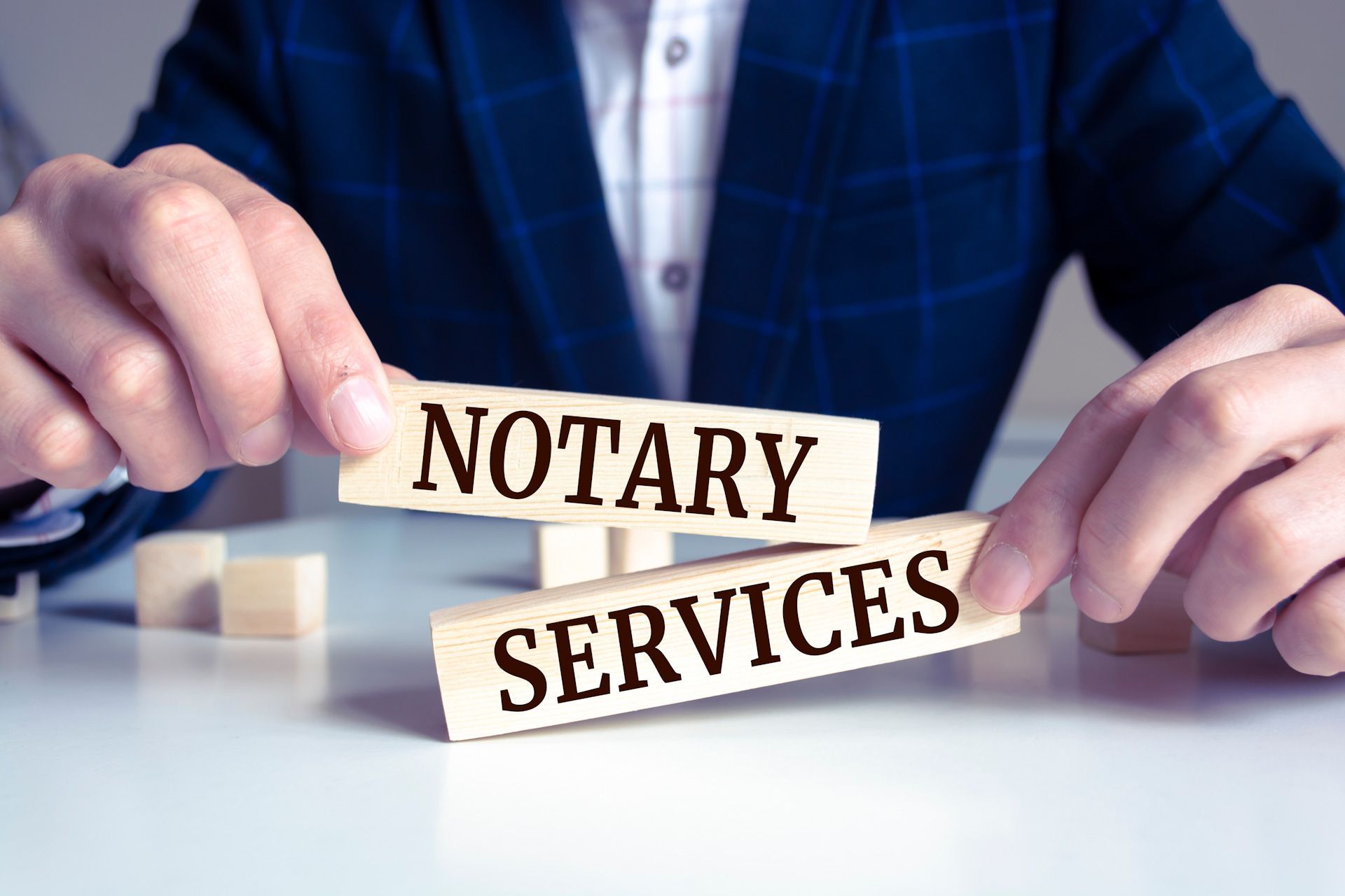 A man is holding wooden blocks with the words notary services written on them.