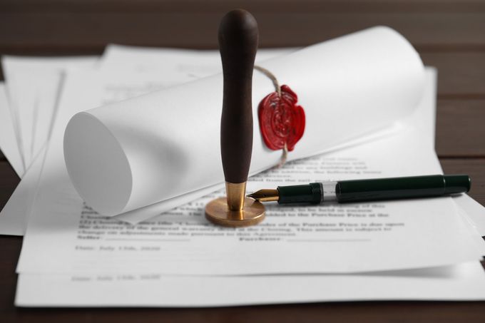 A notary stamp is sitting on top of a piece of paper next to a pen.