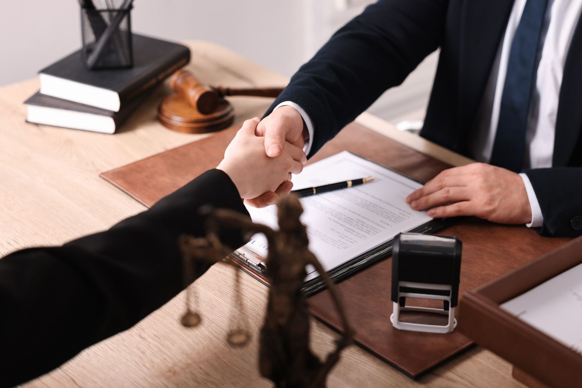 A lawyer is shaking hands with a client while sitting at a desk.