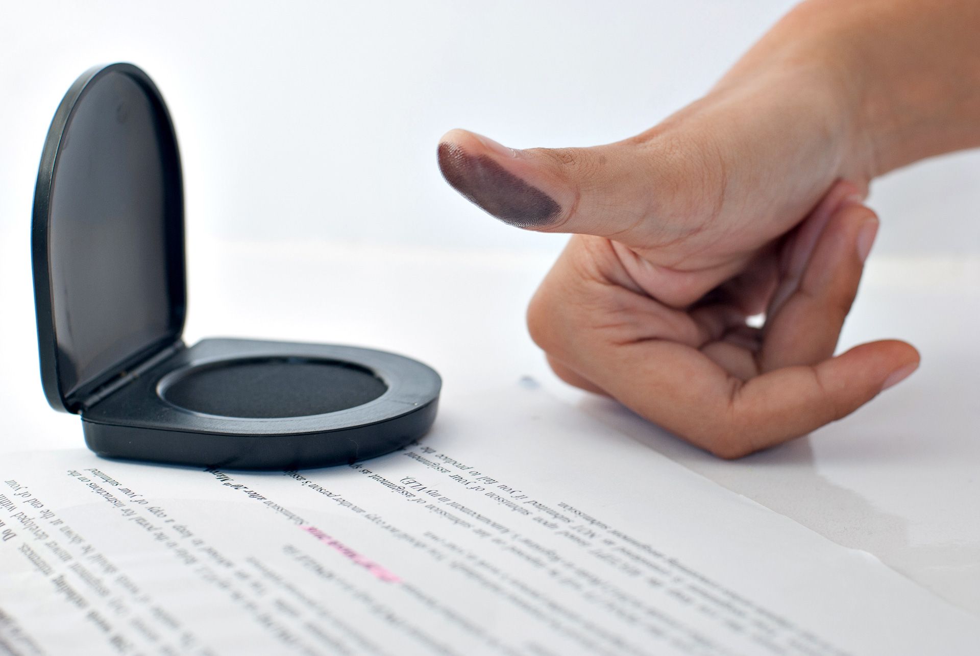 A person is putting their finger in a stamp on a piece of paper.