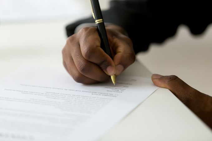 A person is writing on a piece of paper with a pen.