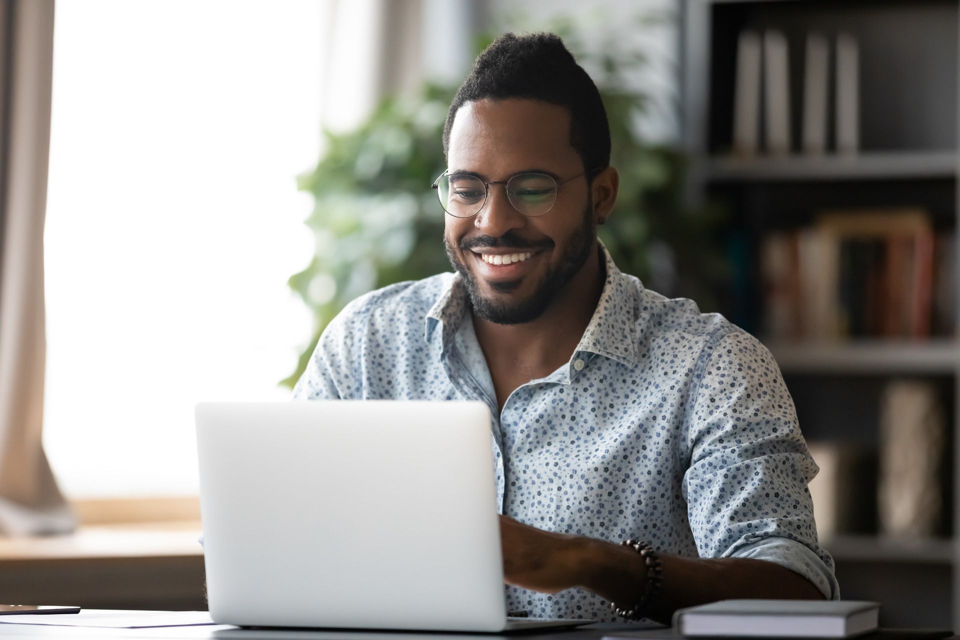 A man is sitting at a desk using a laptop computer.