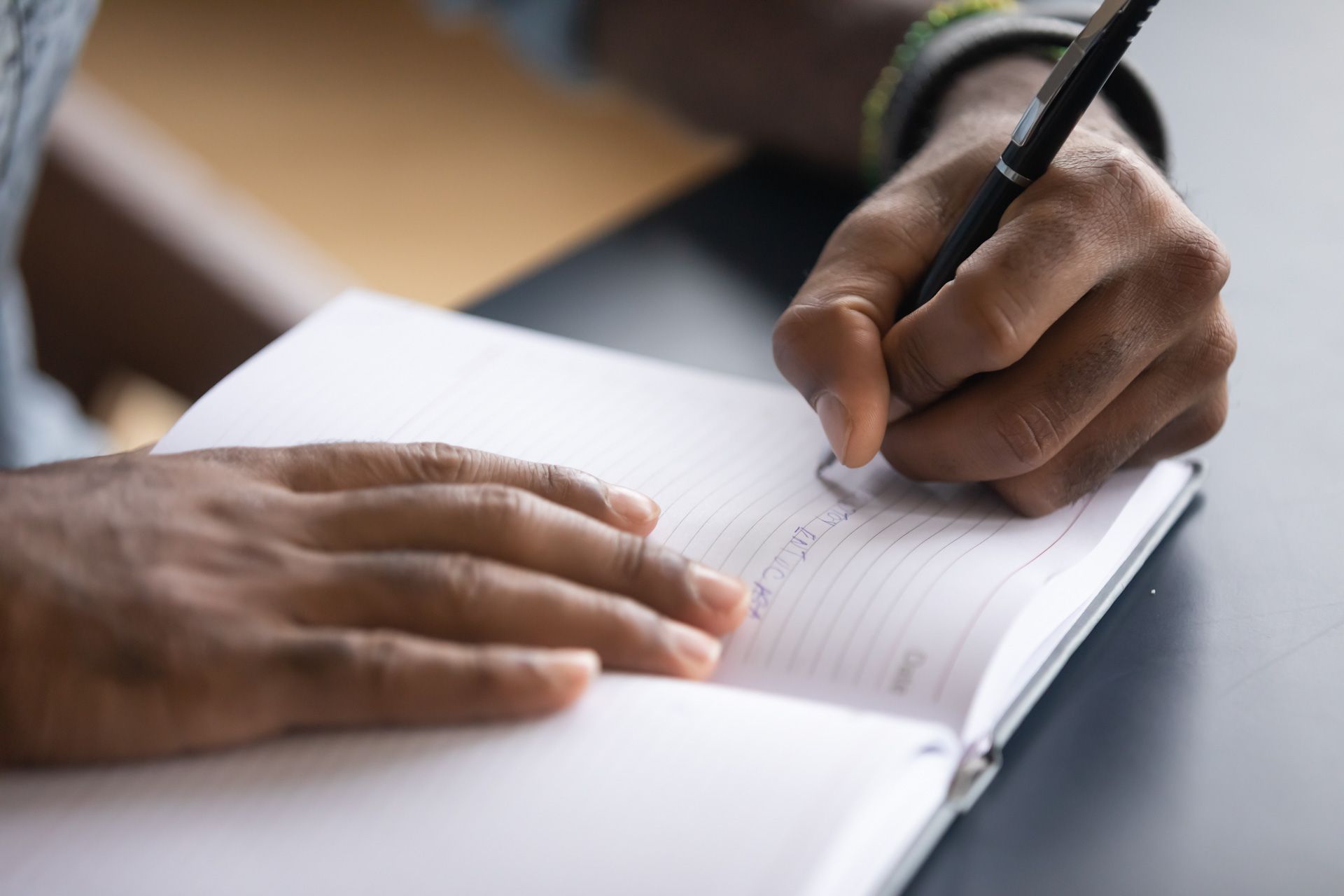 A person is writing in a notebook with a pen.