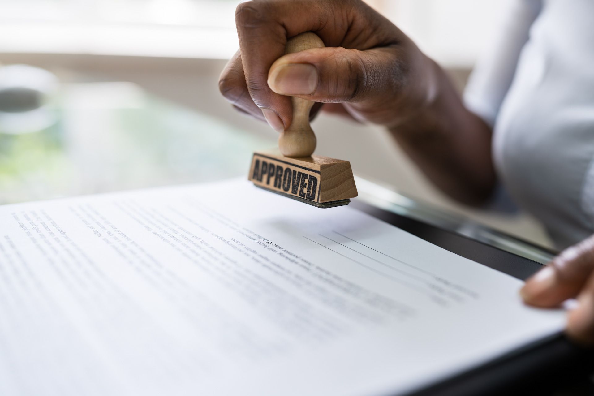 A person is stamping an approved stamp on a piece of paper.
