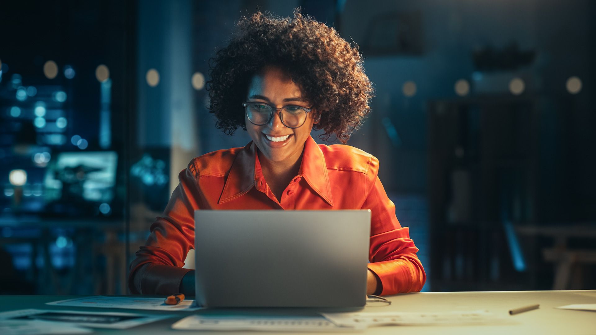 A woman is sitting at a desk using a laptop computer.