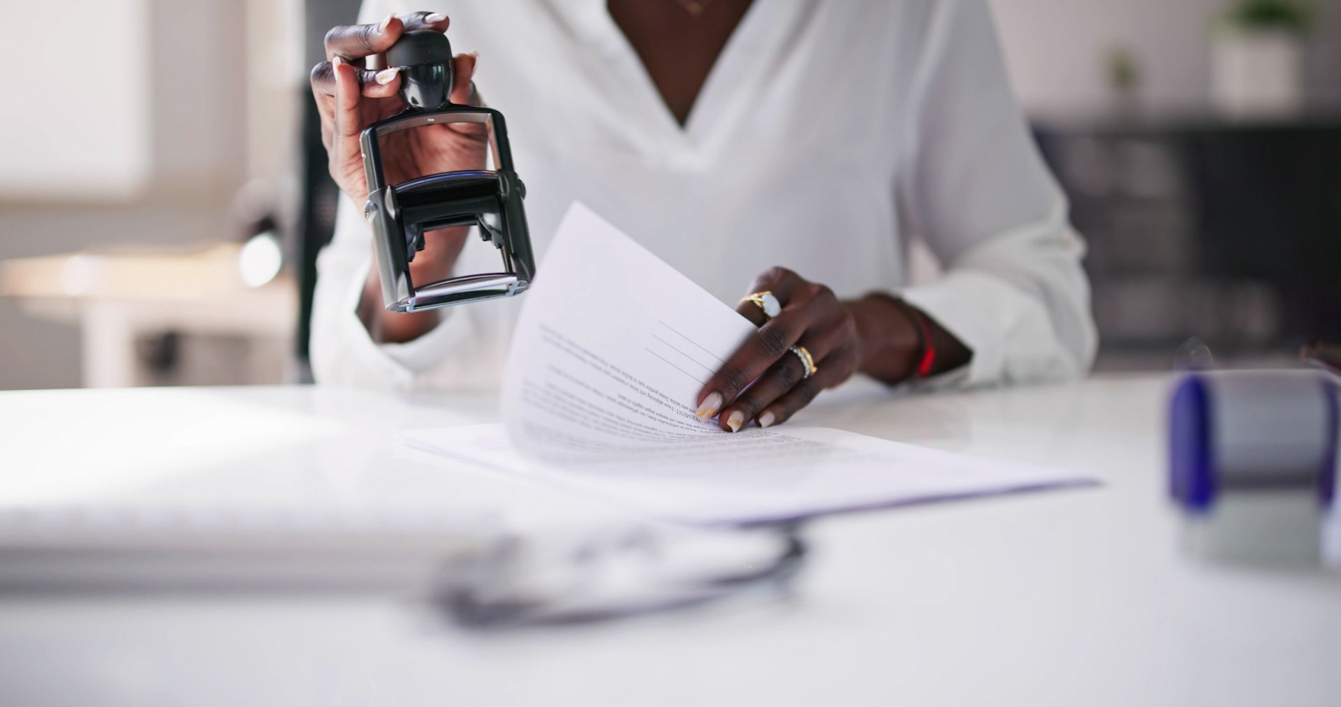 A woman is holding a stamp over a piece of paper.