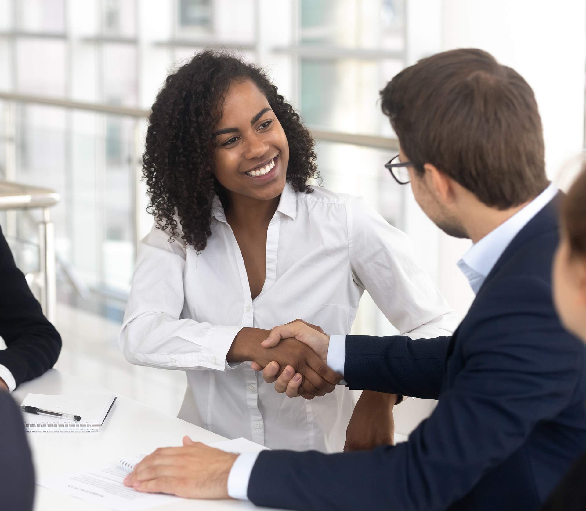 A group of people are sitting around a table shaking hands.