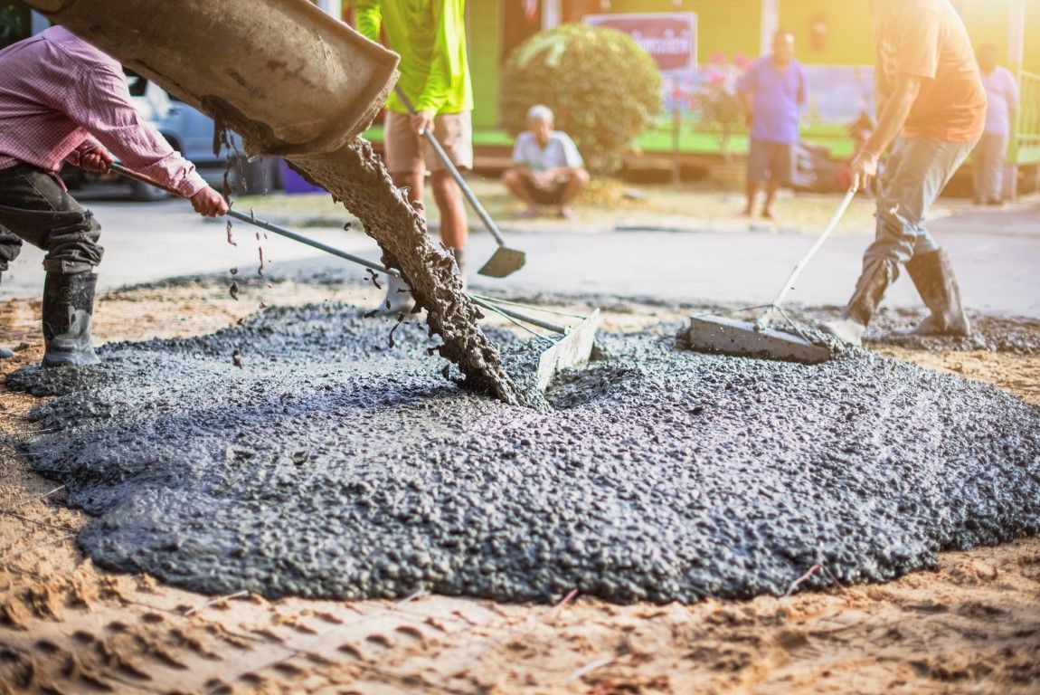 Worker placing concrete with a pump hose for foundation footings in Bushnell