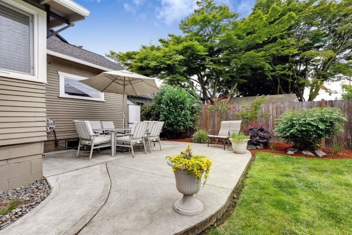 Curved concrete patio with planters and seating beside landscaped backyard in Bushnell