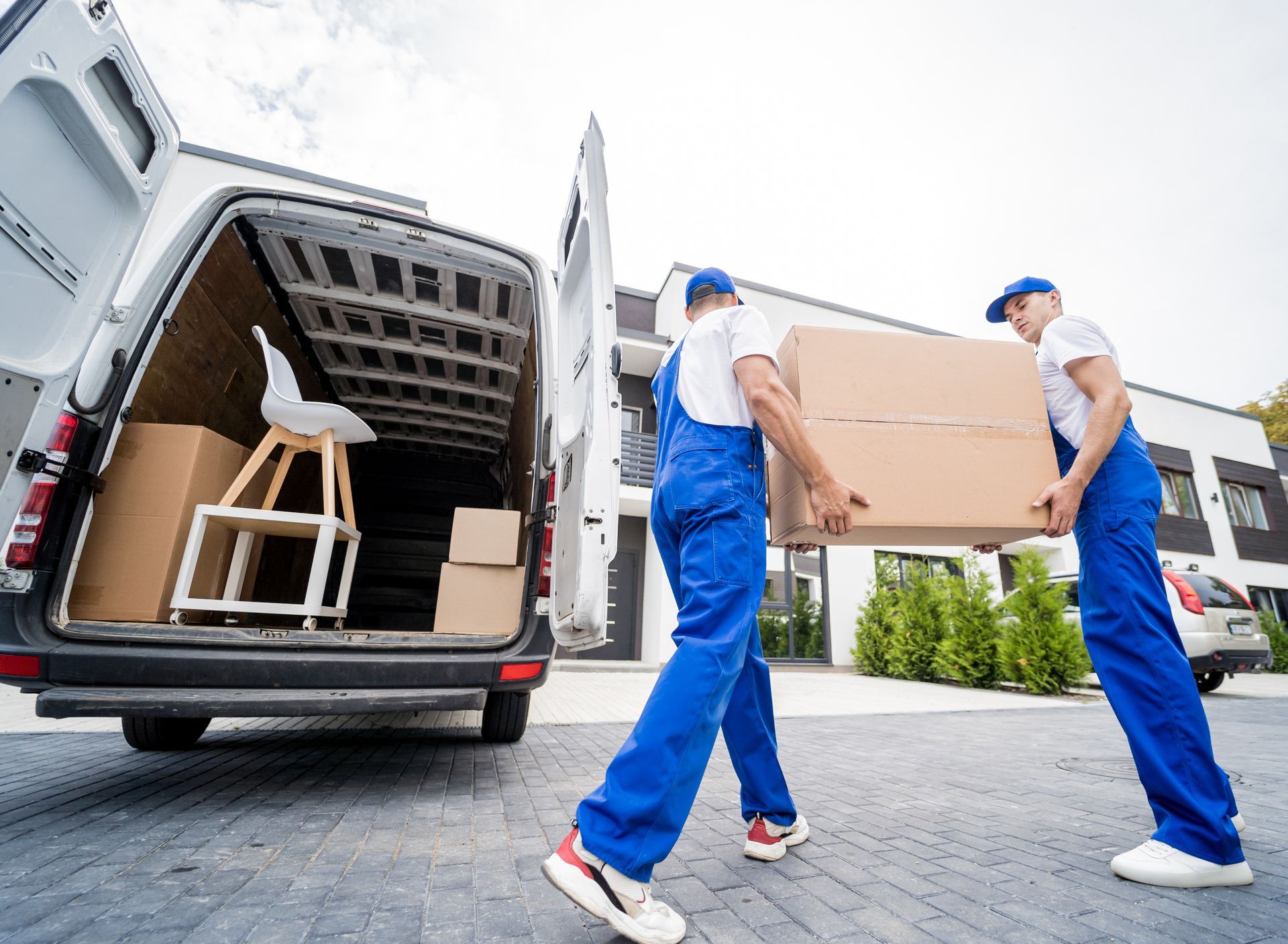 Two men are carrying boxes out of a van.