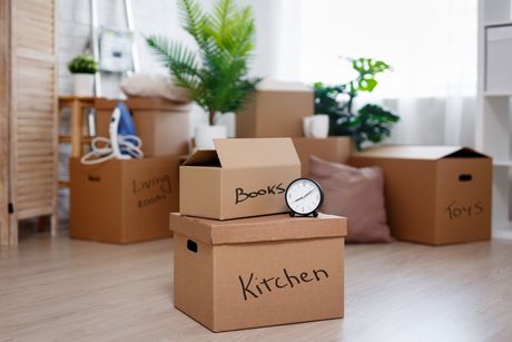 A cardboard box with the word kitchen written on it is stacked on top of another cardboard box.