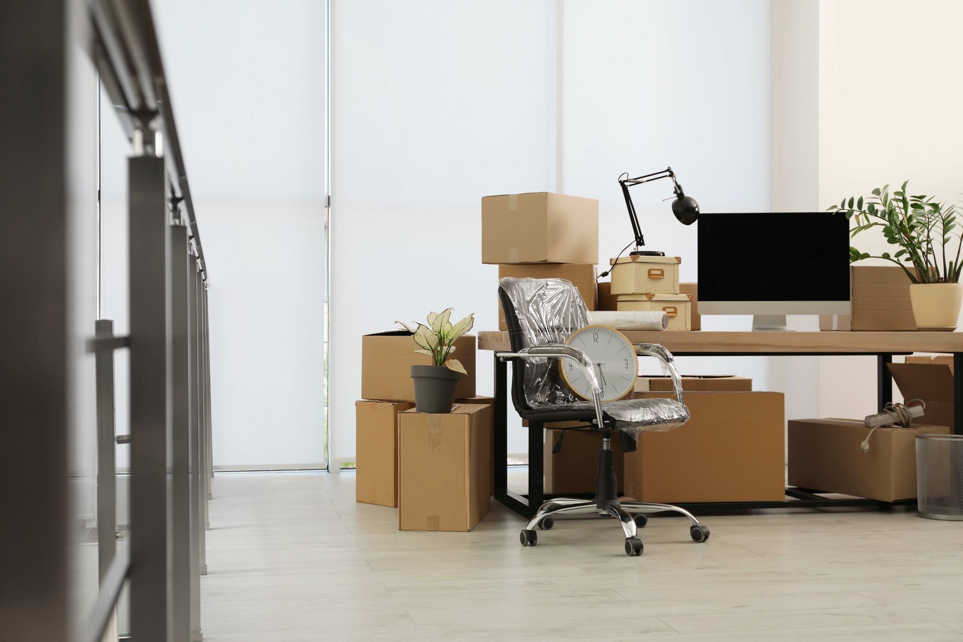 An office with a desk , chair , computer and boxes on the floor.