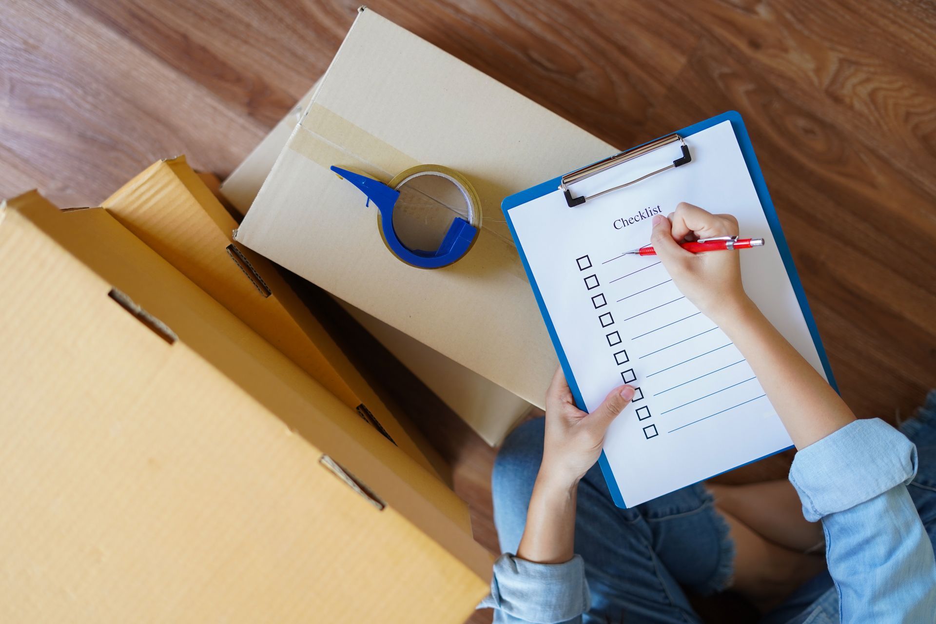 A person is sitting on the floor holding a clipboard and writing on it.