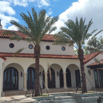 A white house with arches and palm trees in front of it