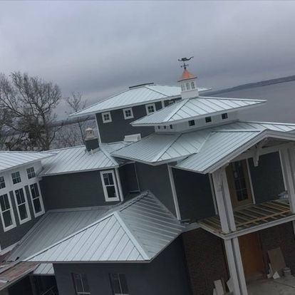 A large house with a metal roof and a weather vane on top of it.