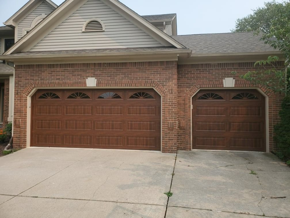 Brown garage doors on a brick building with a concrete driveway. A two-car garage and a single-car garage are visible.