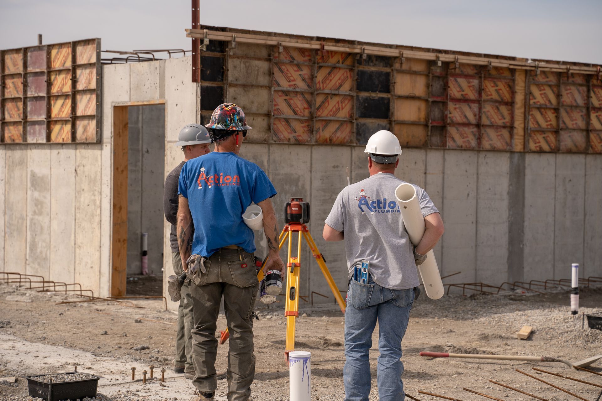 a group of plumbing workers are standing in front of a building under construction .