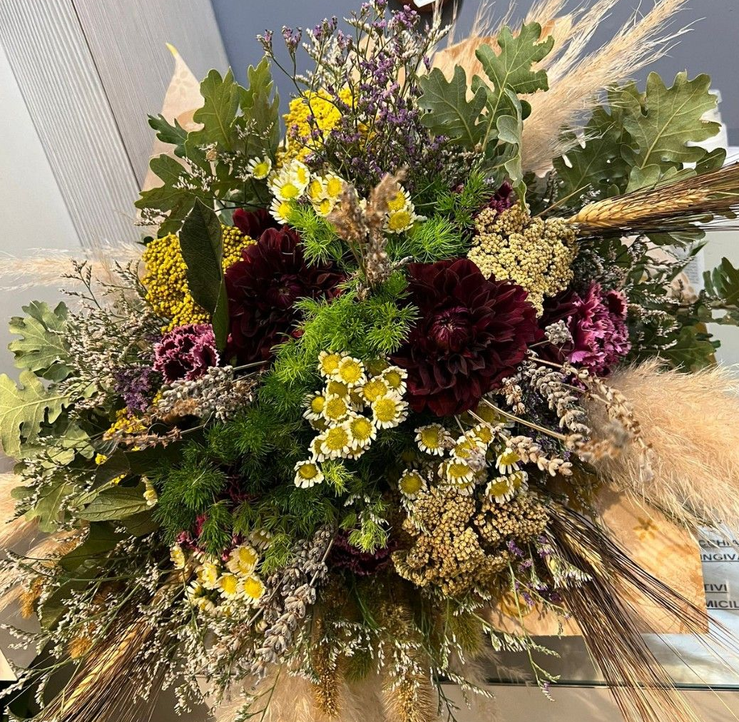 Bouquet di fiori secchi nelle tonalità del bordeaux, giallo e verde, con accenti di grano.