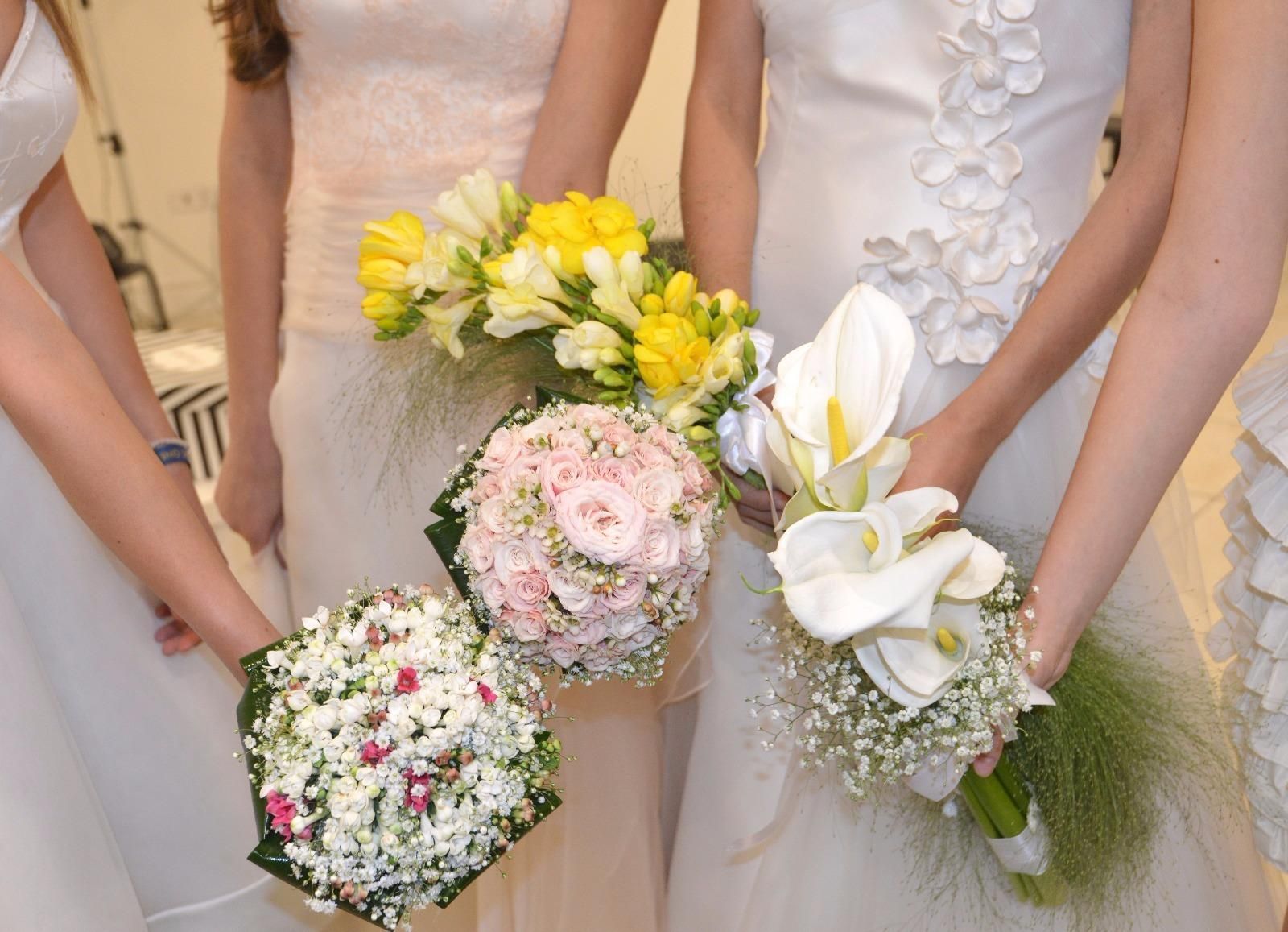 Le damigelle in abiti bianchi tengono in mano bouquet di fiori vari, all'interno.