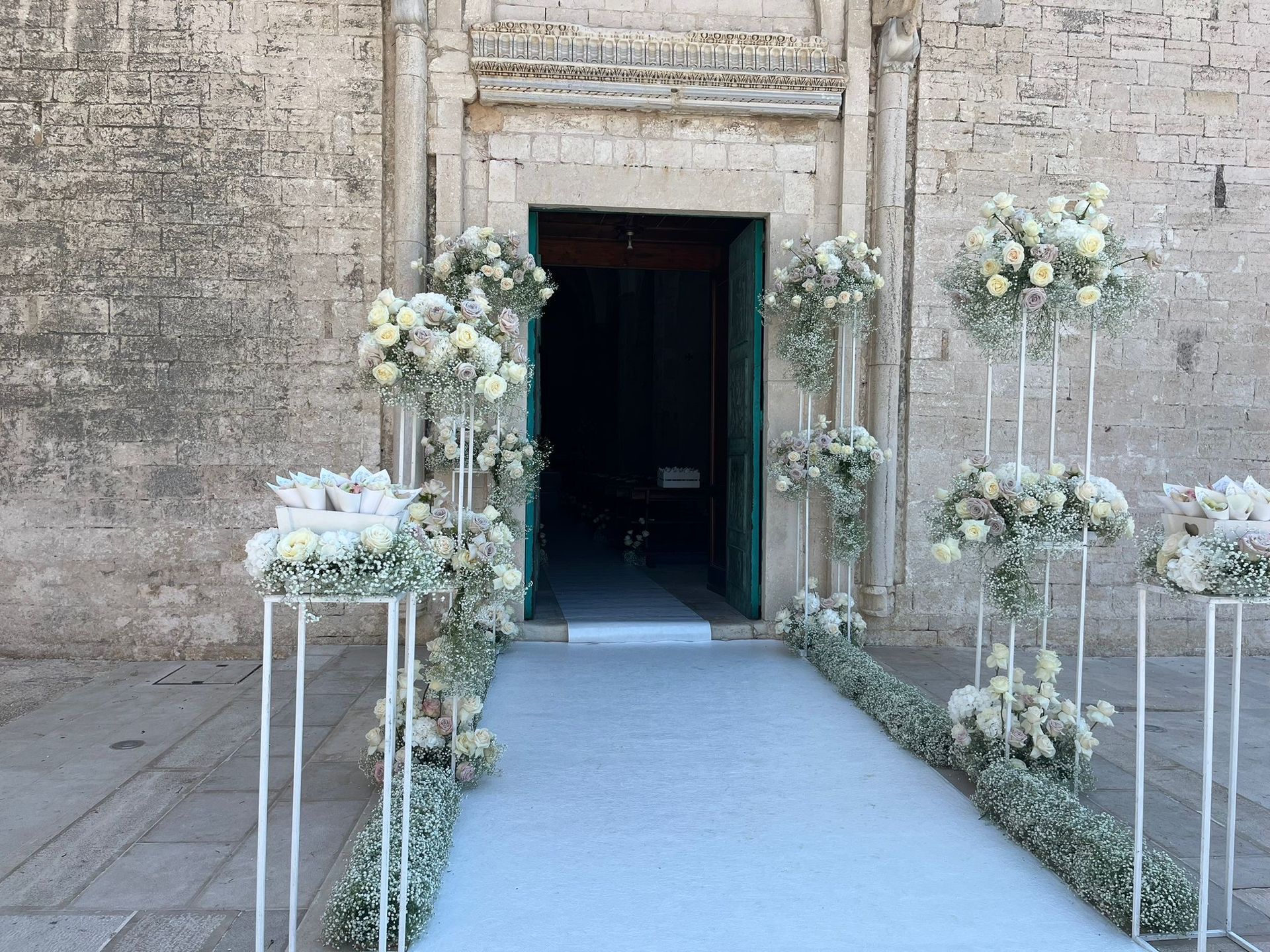 Ingresso per le nozze decorato con fiori bianchi e un tappeto azzurro che conduce alla porta della chiesa.
