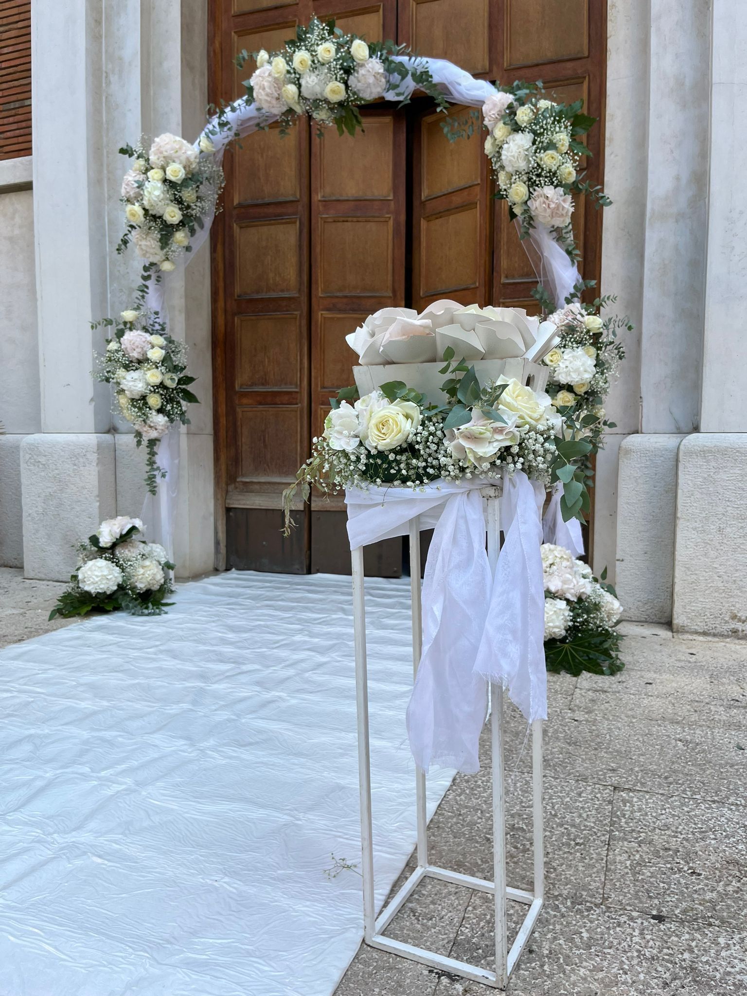 Composizione floreale con rose bianche e ortensie, con decorazioni in gypsophila e nastri.