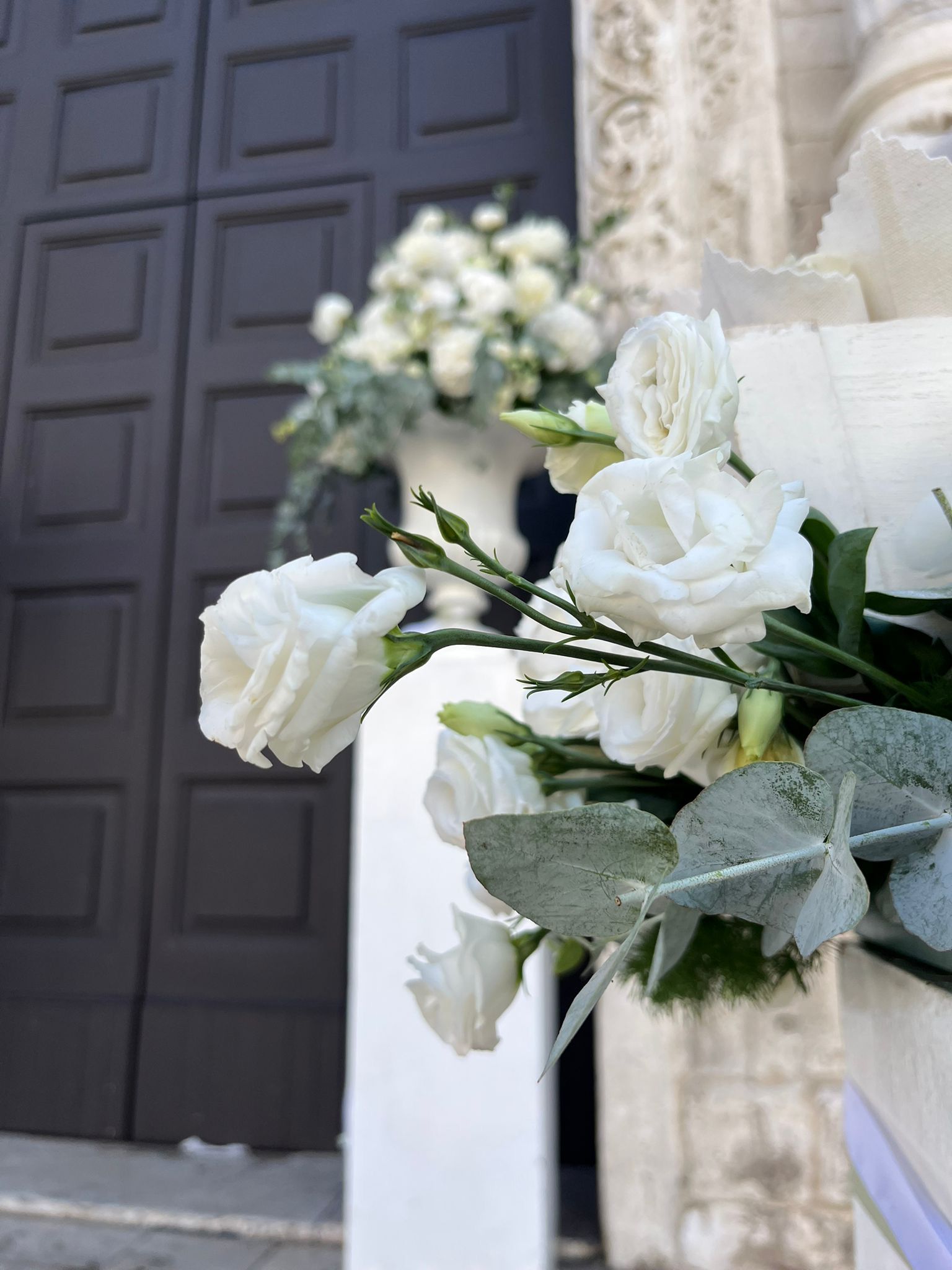 Fiori bianchi e verde decorano l'ingresso di una chiesa.