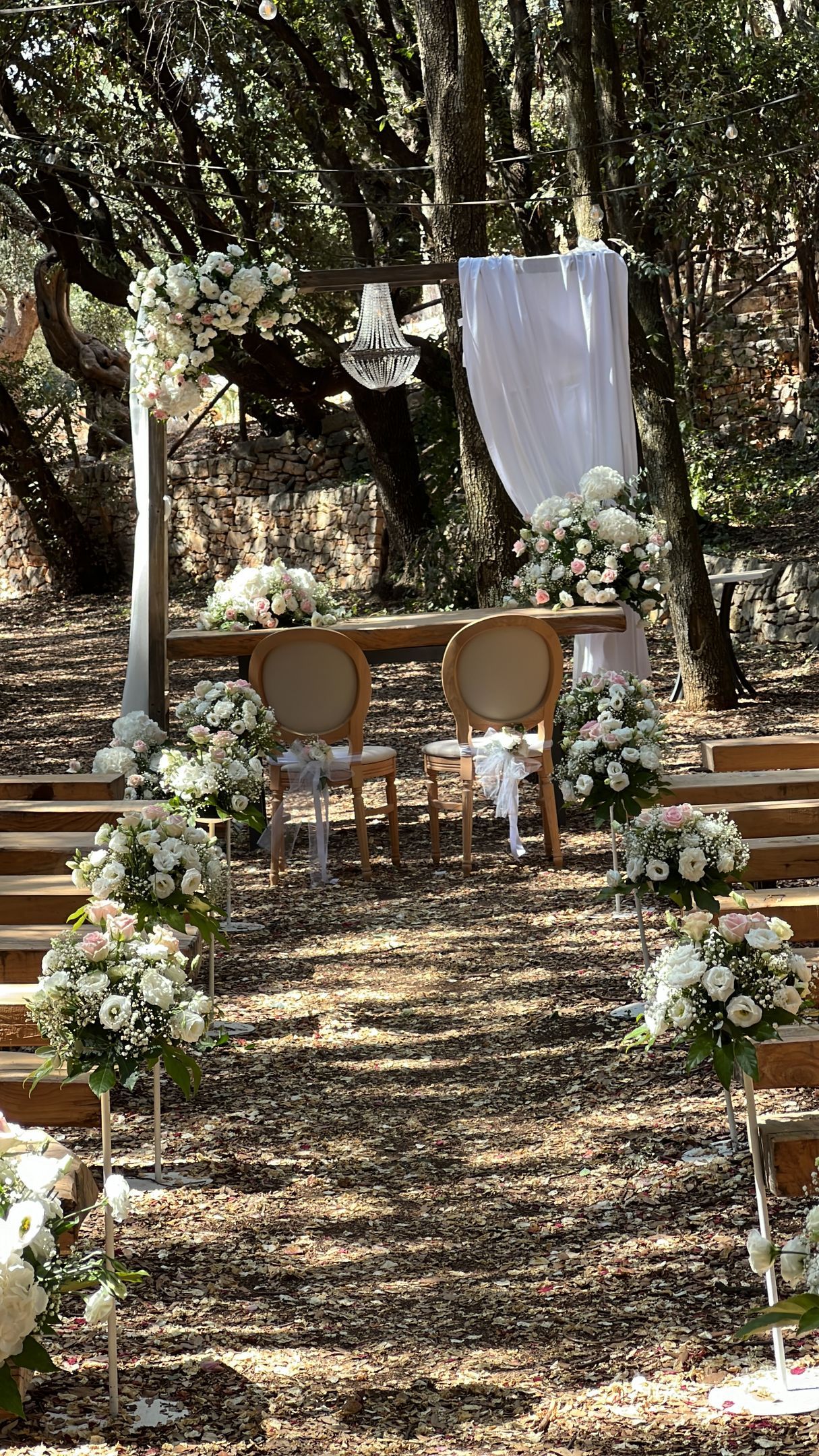 Arco floreale a forma di cuore decorato con fiori bianchi, con vista sull'oceano blu. Due sedie sono rivolte verso l'oceano.