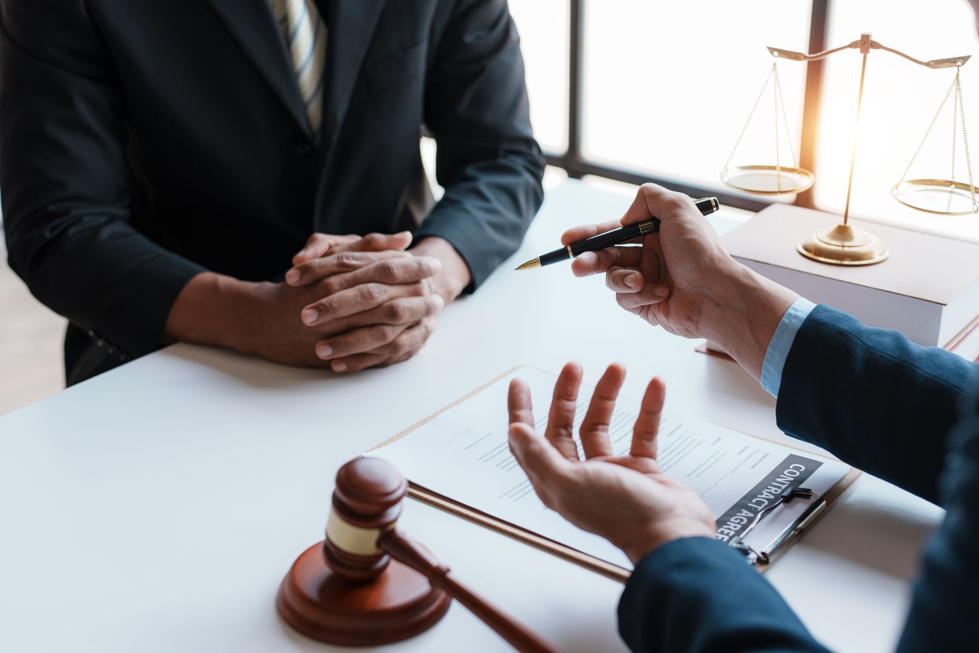 Lawyer consultation at desk with gavel, scales of justice, and notes on a clipboard