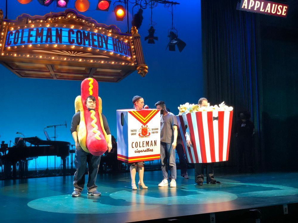 A group of people standing on a stage in front of a sign that says coleman comedy house