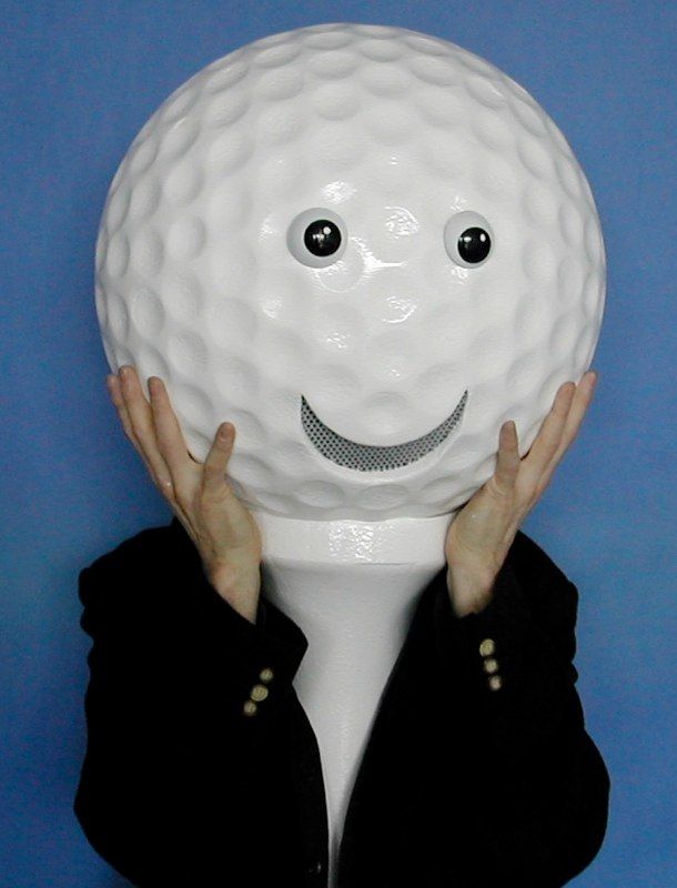 A person holding a golf ball with a face on it