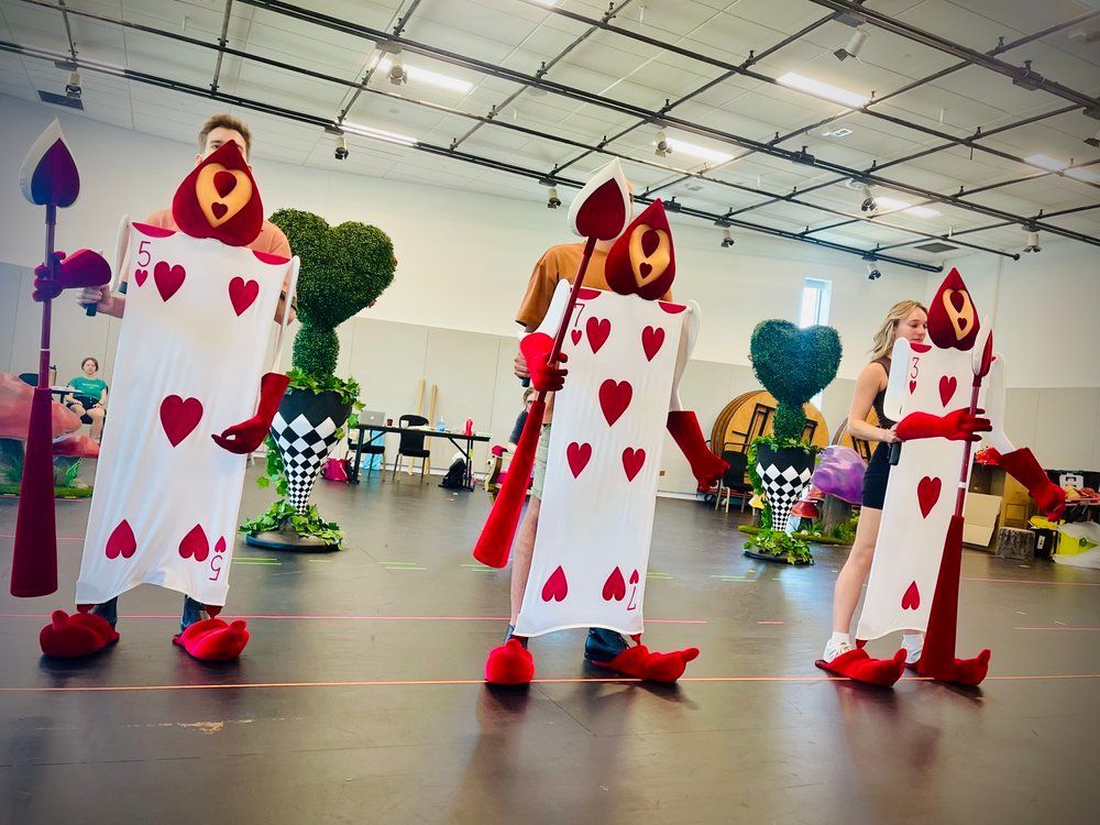 A group of people dressed as queen of hearts from alice in wonderland are standing in a room.