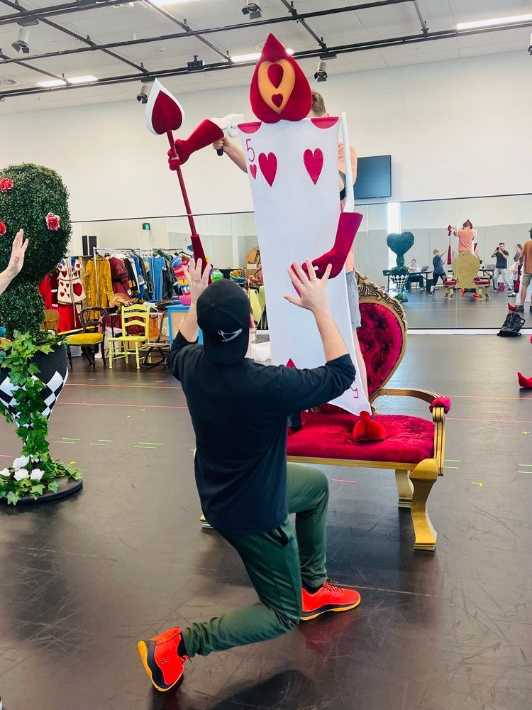 A man is kneeling down in front of a card that says queen of hearts