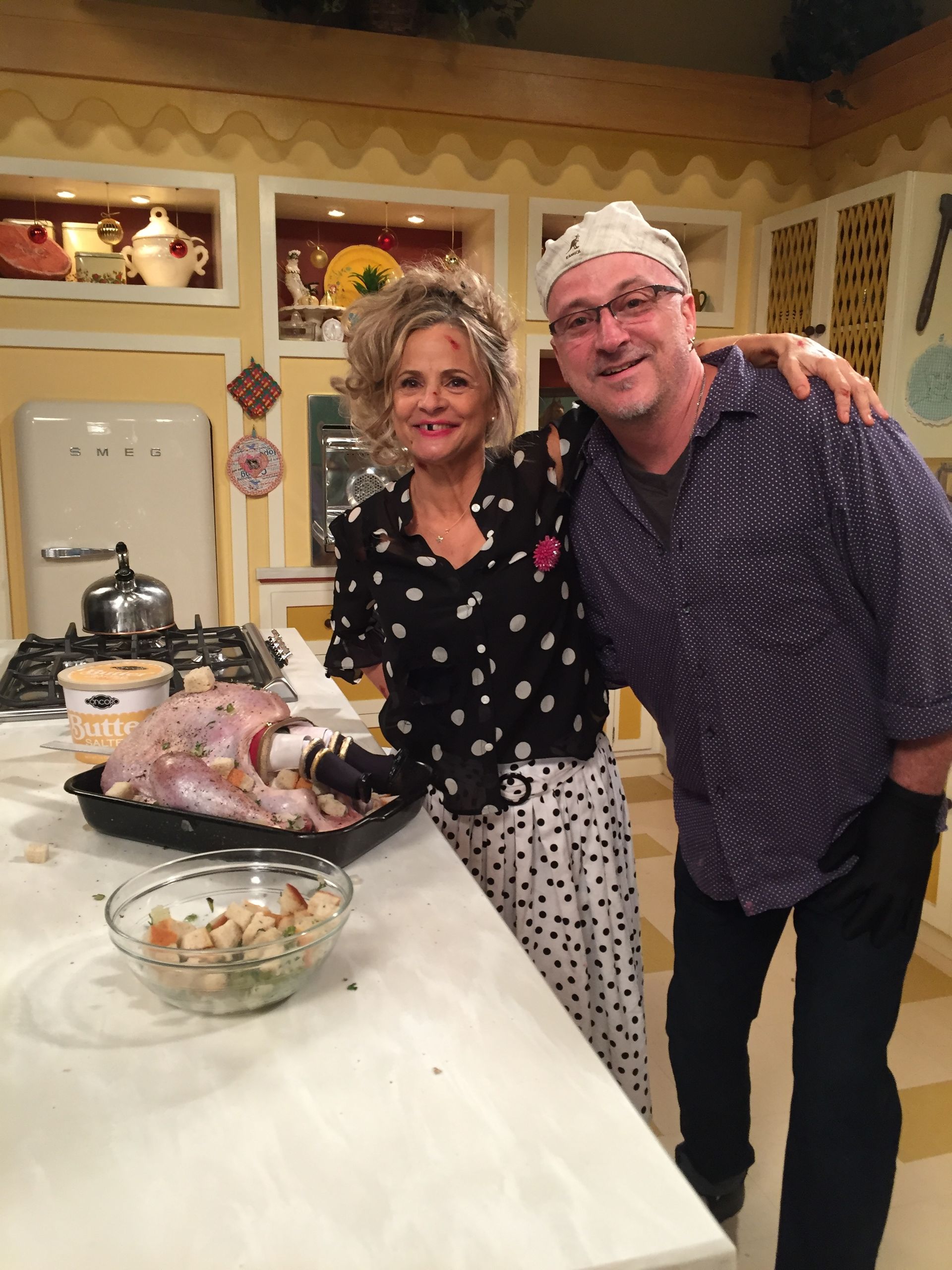 A man and a woman are posing for a picture in a kitchen