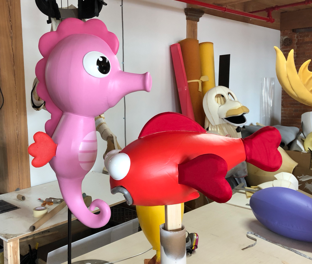 A pink seahorse next to a red fish on a table