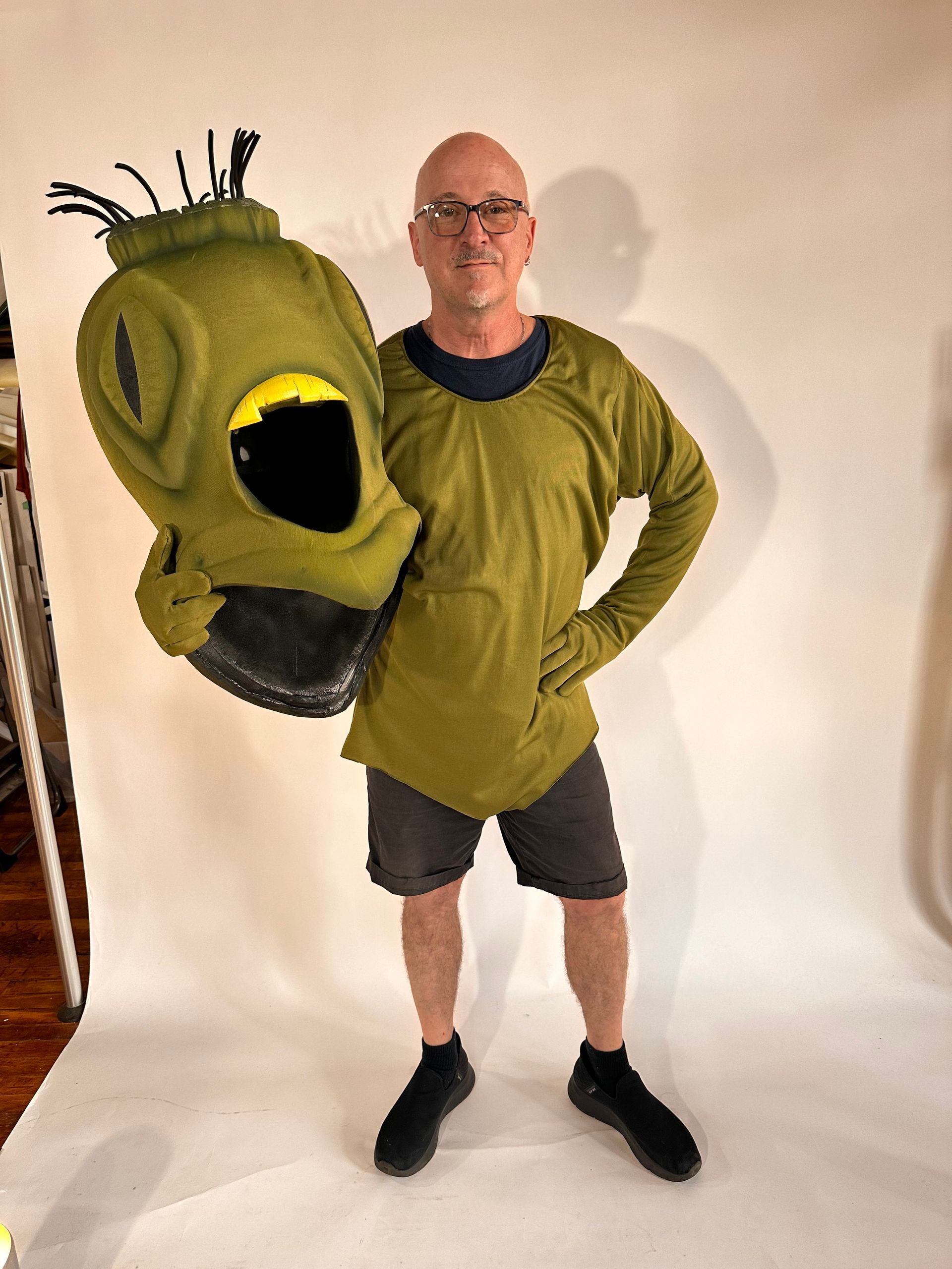 A man in a green shirt is holding a green mask