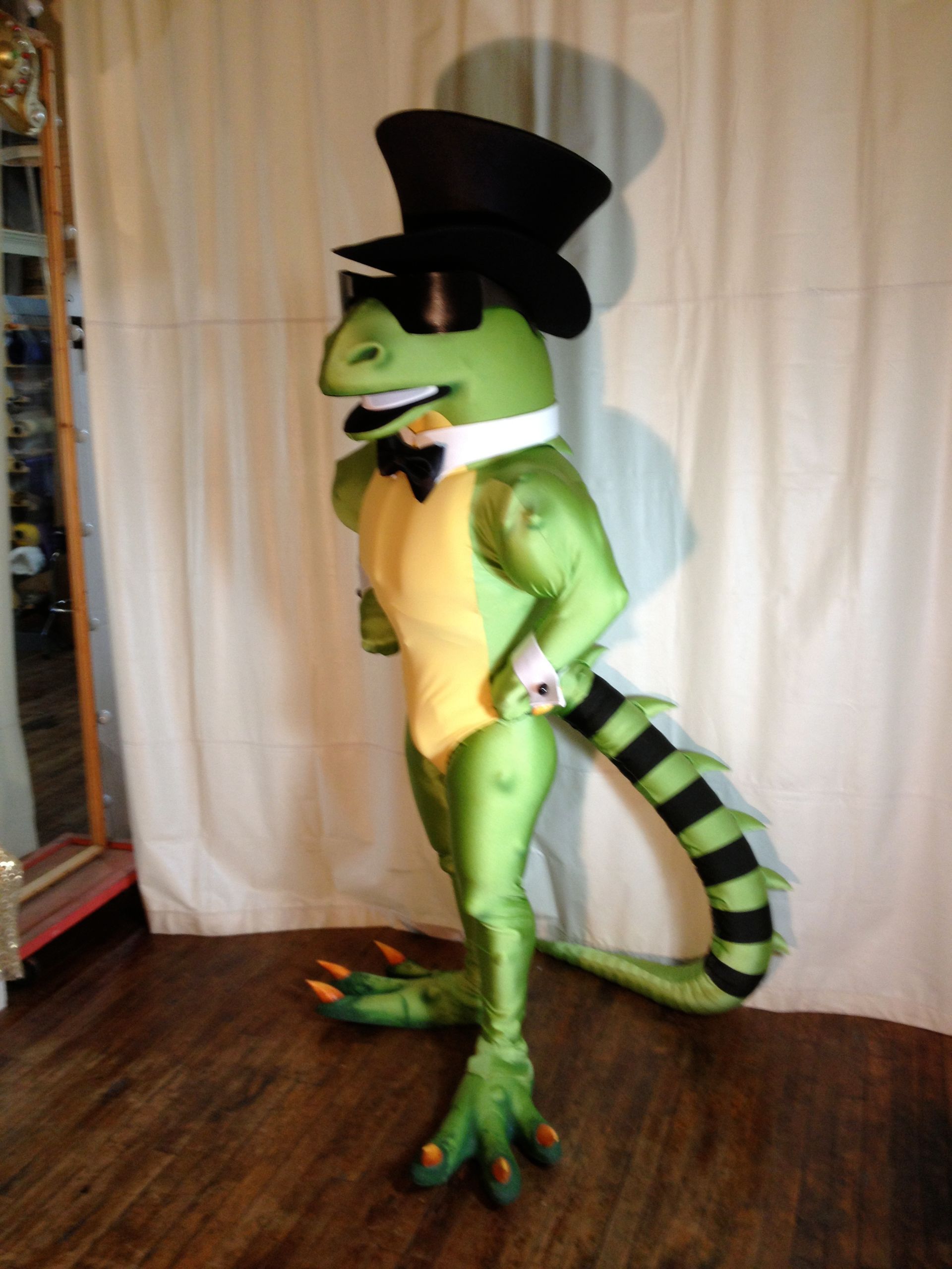 A green lizard wearing a top hat and sunglasses