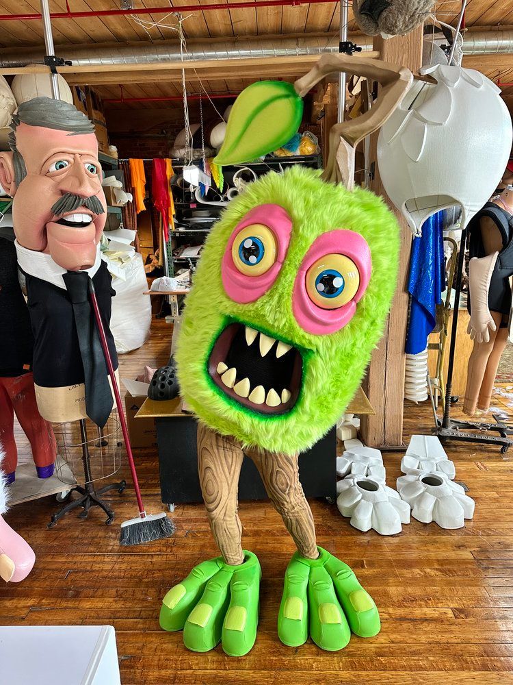 A green monster mascot is standing next to a man in a suit and tie.