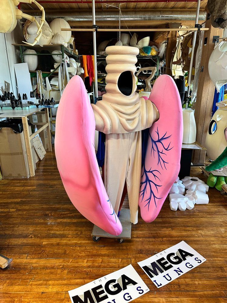 A statue of a person with pink lungs is sitting on a wooden floor.