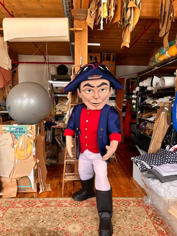 A mascot in a pirate costume is standing in a room.