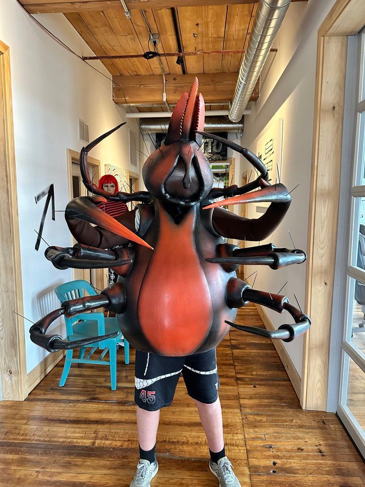 A man in a cockroach costume is standing in a hallway.