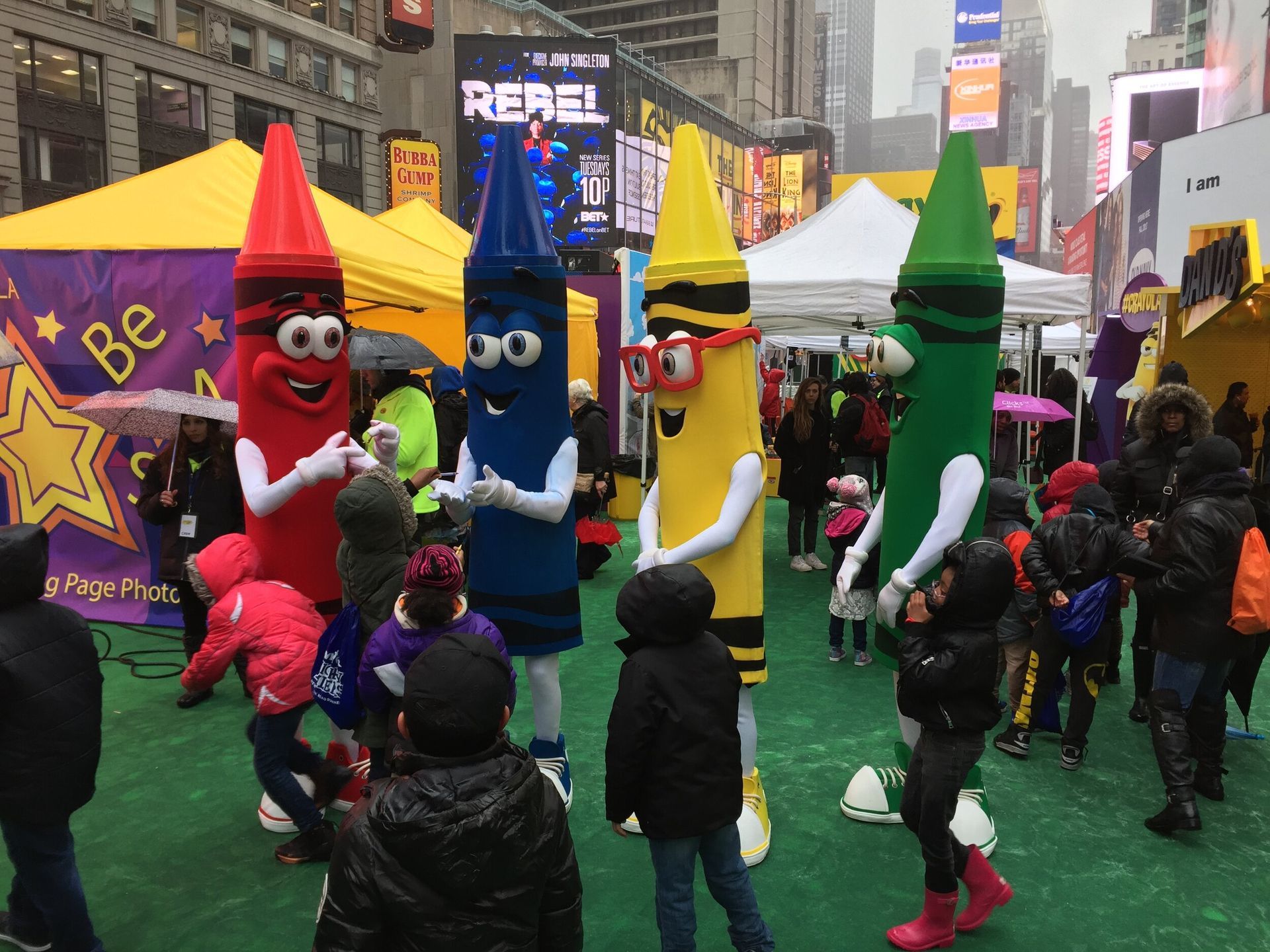A group of crayon mascots are standing in front of a crowd of people.