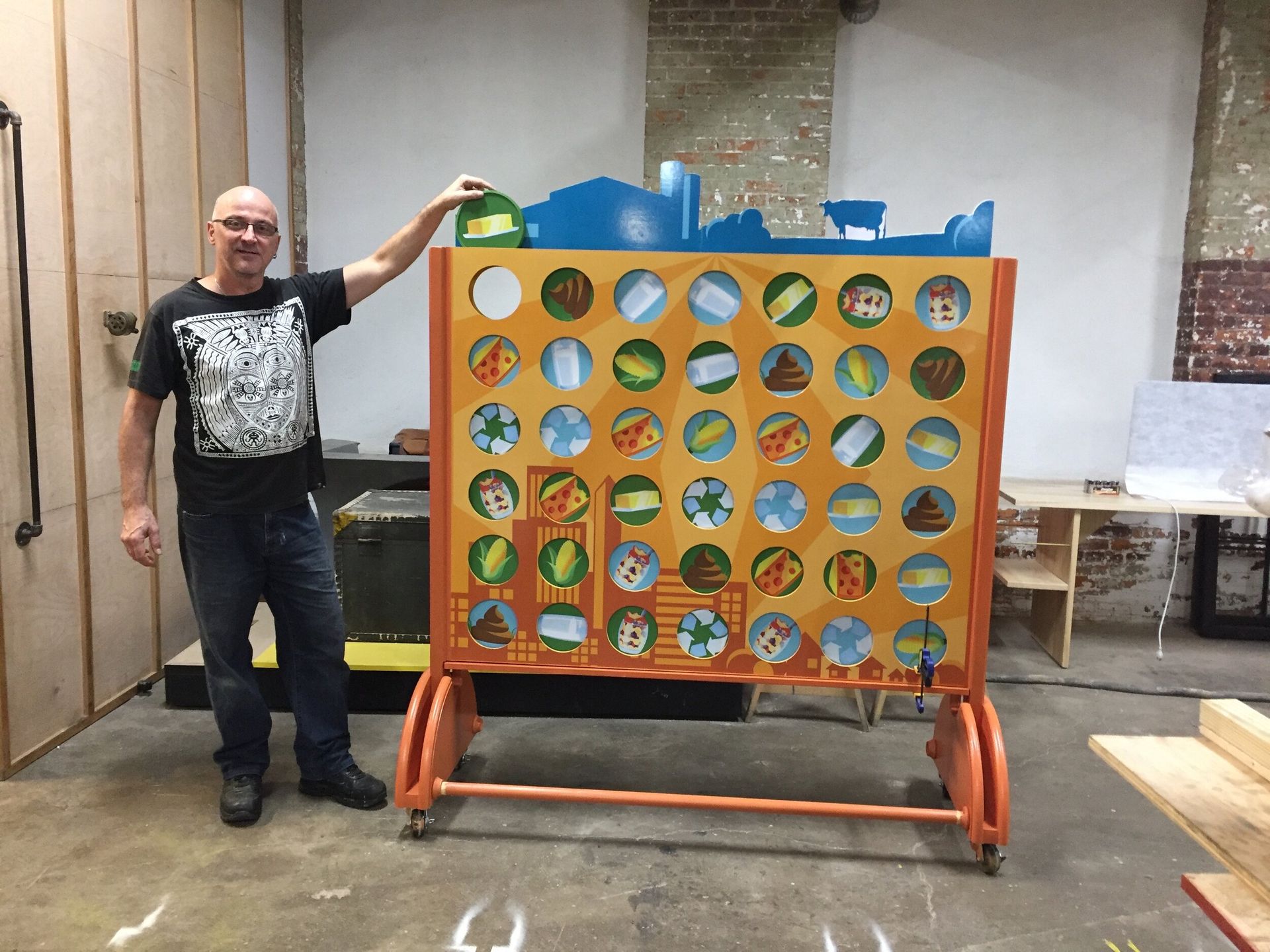 A man is standing next to a giant connect four game.