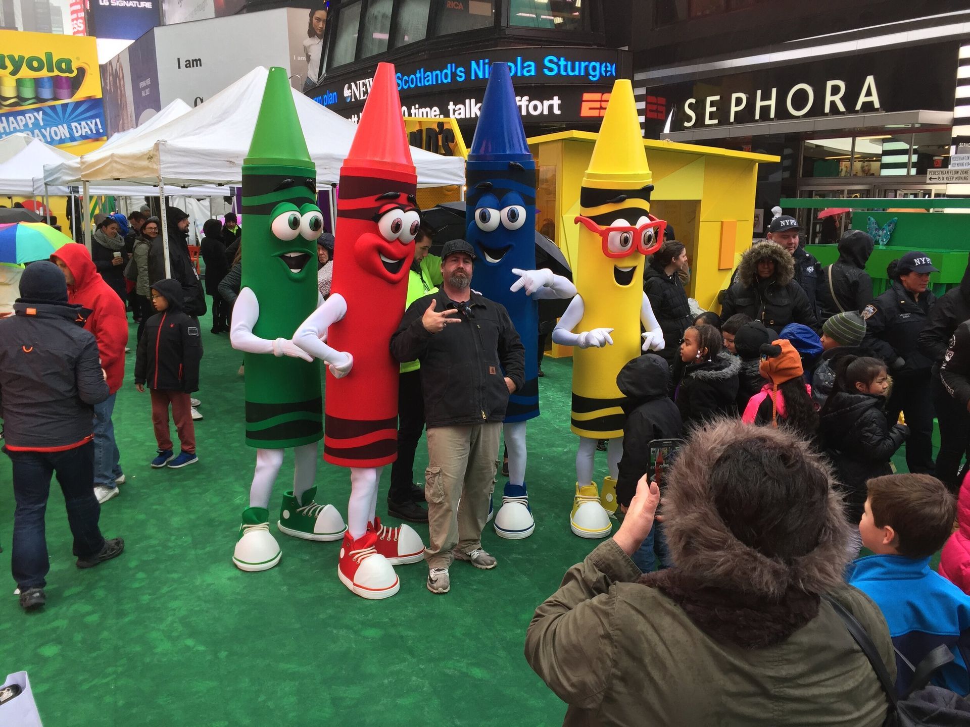 A woman taking a picture of a group of crayon mascots