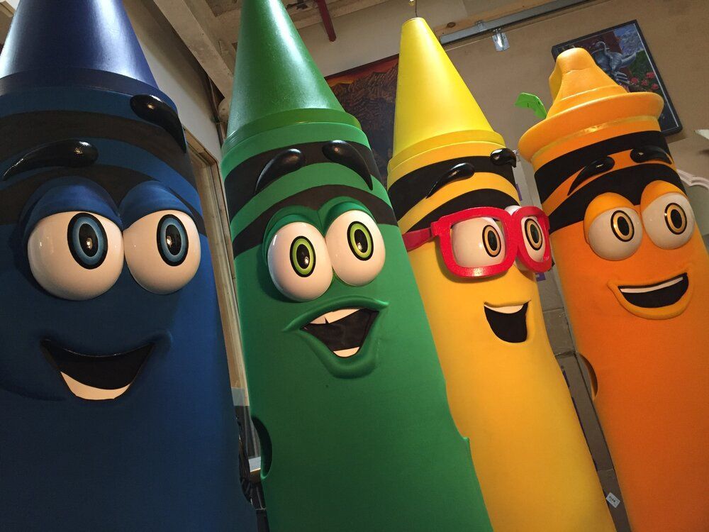 Four cartoon crayons are standing next to each other