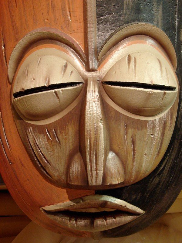 A close up of a wooden mask with its eyes closed