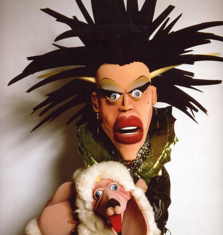 A puppet of a woman holding a sheep with its mouth open