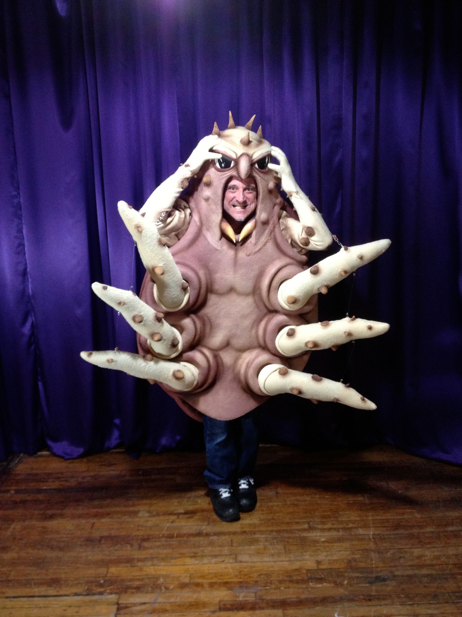 A person in a costume with a purple curtain behind them